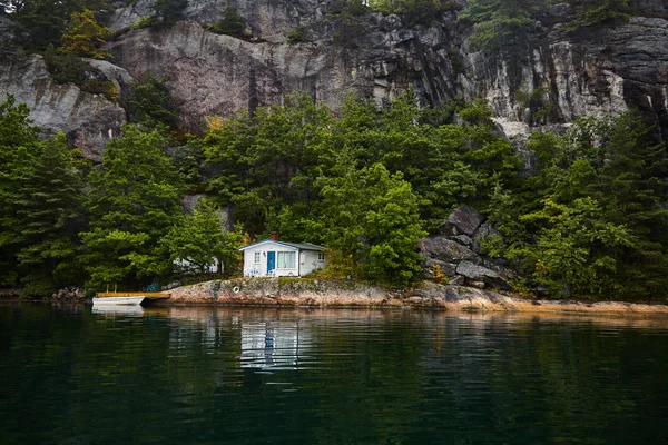Ein einsames Haus am Ufer in einem norwegischen Fjord lizenzfreie Stockfotos