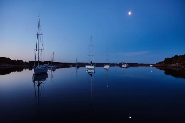 Zeilboten's nacht verlicht verankerd in rustige zomeravond Stockfoto