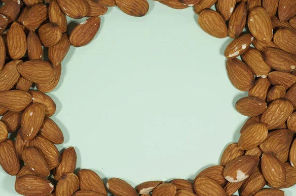 Pastel yeşil arkaplanda badem çerçevesini daire içine al