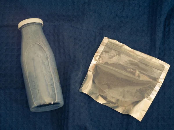 Batido azul de matcha y arándano en botella de vidrio y polvo de matcha en bolsa de cierre con cremallera en toalla de cocina azul —  Fotos de Stock