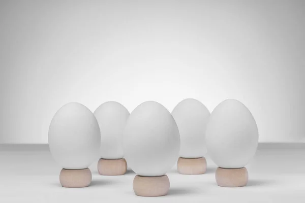 Пять белых куриных яиц на деревянных стендах на белом фоне для копирования пространства Стоковая Картинка