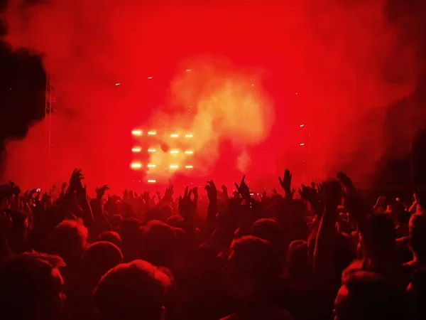 Толпа с поднятыми руками под сценой в красном дыму Лицензионные Стоковые Изображения