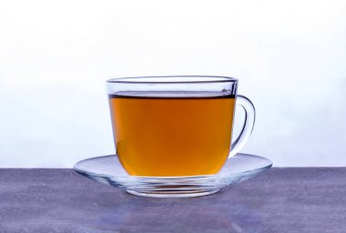 Şeffaf cam bardak ve siyah çay ışık kaynağında duruyor.