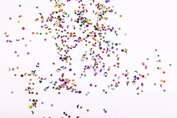 Lantejoulas coloridas dispersas de várias formas em um fundo branco — Fotografia de Stock