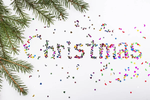 Frame with fir branches and the word Christmas written in colored sequins of various shapes — ストック写真