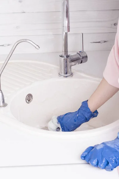 a residential cleaning service worker washes the kitchen sink