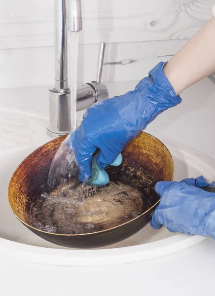 Mãos em luvas azuis lavar a panela na cozinha brilhante — Fotografia de Stock
