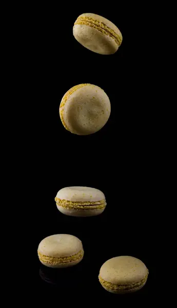 Yellow macaroons fall down on a black background — Stock Photo, Image