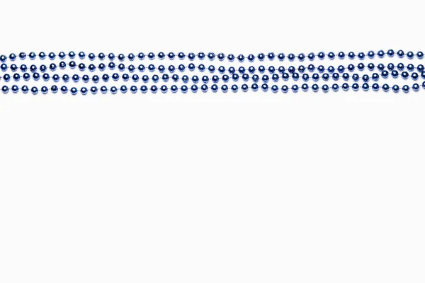 Perline disposte in file diritte su Mardi Gras blu su sfondo bianco — Foto Stock