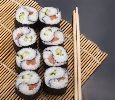 Lezzetli Yin Yang suşisi siyah arka planda sopalarla bir mindere yuvarlanıyor.