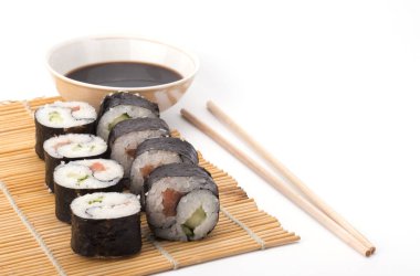 Lezzetli Yin Yang suşisi beyaz arka planda çubuklarla bir mindere yuvarlanıyor.