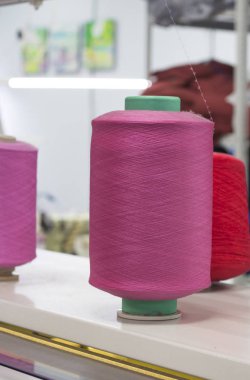 İşteki bir örgü makinesinde pembe elastik iplikli bobinler.