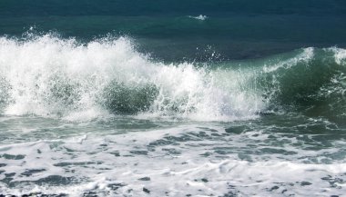 Küçük bir fırtına sırasında kıyıya vuran mavi bir deniz dalgası.