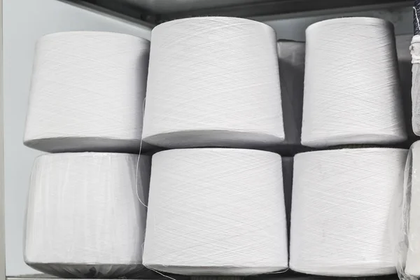 Hilos de algodón blanco enrollados en bobinas de pie en un estante en la fábrica —  Fotos de Stock