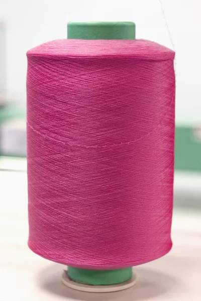 bobbin with pink elastic yarn on knitting machine