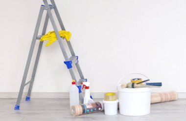 Boya kutuları ve aletlerle dolu bir merdiven. Işıkla yenilenmiş bir duvara karşı.