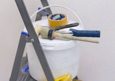 Bir kova boya ve merdiven üzerindeki aletler.