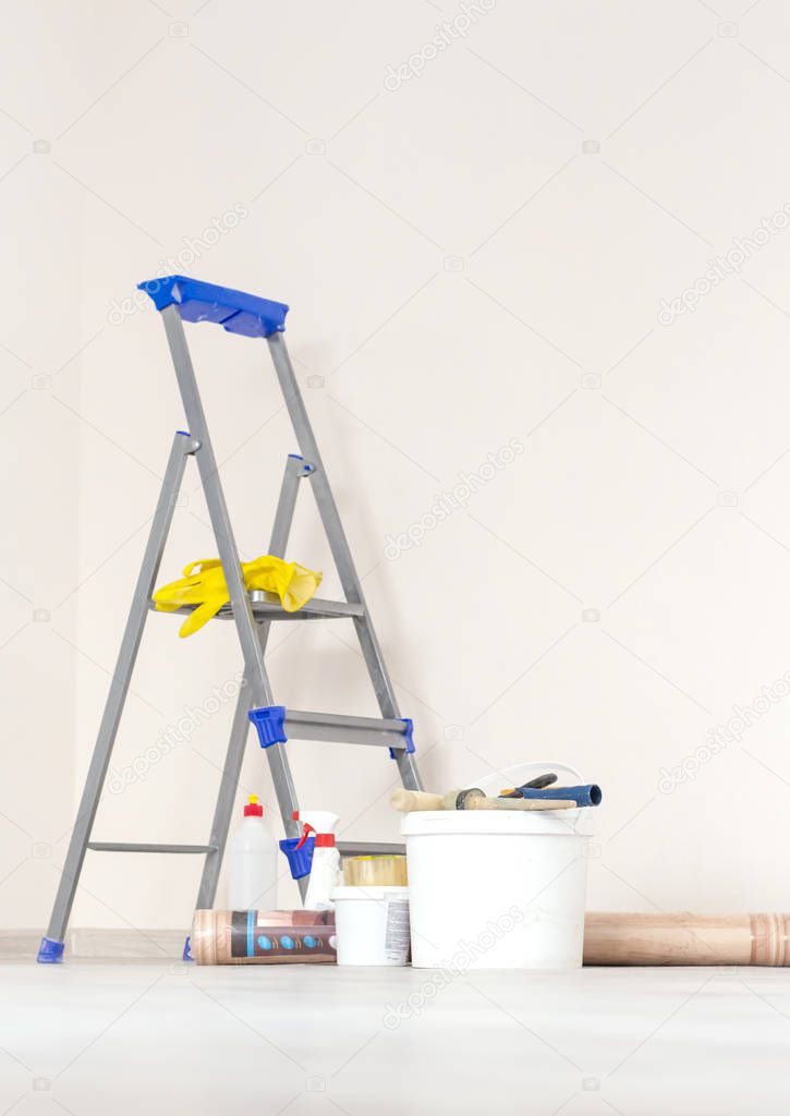 a stepladder with paint cans and tools in a bright renovated room