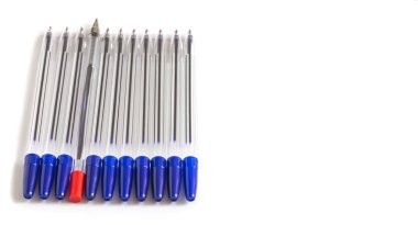 Beyaz arkaplandaki mavi tükenmez kalemler arasında bir kırmızı tükenmez kalem