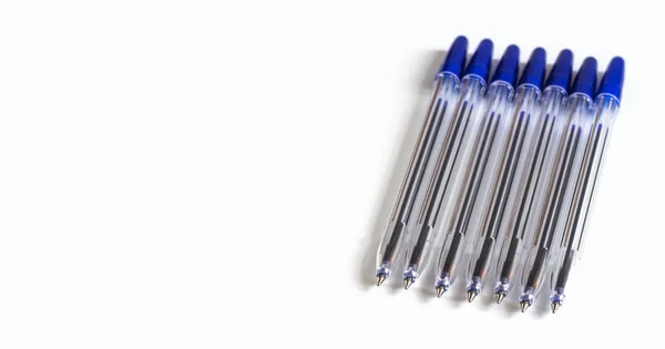 Lots of transparent ballpoint pens with a blue cap on a white background — 스톡 사진