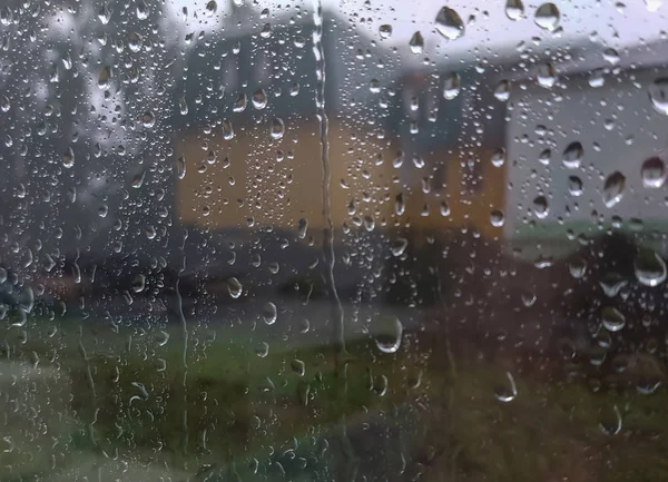 Afuera de la ventana está lloviendo fuertemente, gotas de lluvia en la ventana —  Fotos de Stock