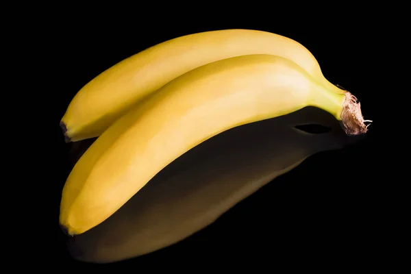 Dos plátanos amarillos yacen sobre un fondo negro — Foto de Stock