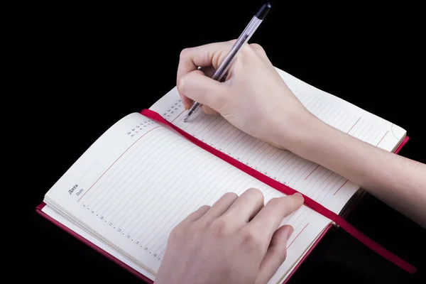 Ręka Kobiety Pisze Długopisem Czerwonym Notatniku Czarnym Tle — Zdjęcie stockowe