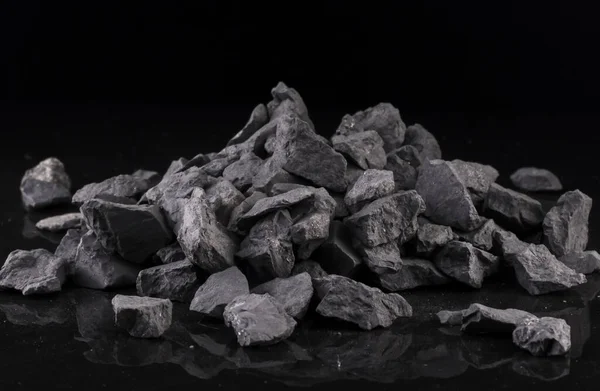 Bir karbon minerali olan mineral shungite, siyah arka planda olağanüstü su arıtma kalitesi sağlar..