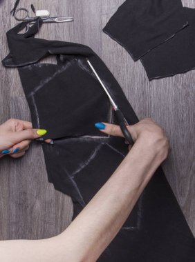 Bir kadın koruyucu yüz maskeleri için evde covid-19 salgını sırasında makas kesiyor..