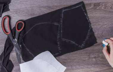 Koruyucu maskeleri evde dikmek için siyah kumaşa tebeşirle çizilmiş detaylar.