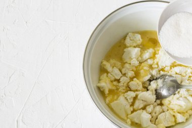 Süzme peynirli turta için doldurma hazırlığı, süzme peyniri şeker ve yumurtayla karıştır.