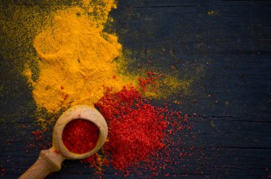 Sarı ve kırmızı köri baharatı ve siyah ahşap arka planda tahta kaşıkla kırmızı biber. Yakın plan..