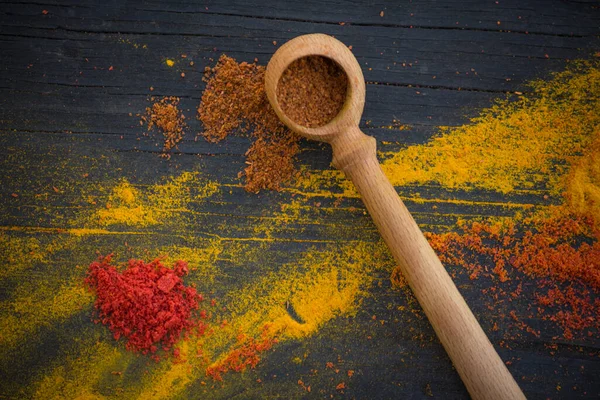 Houten Lepel Met Paprika Verspreide Gele Rode Specerijen Een Zwarte — Stockfoto