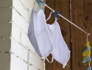 Yeniden kullanılabilir beyaz tıbbi maskeler çamaşır ipinde yıkandıktan sonra kurur..