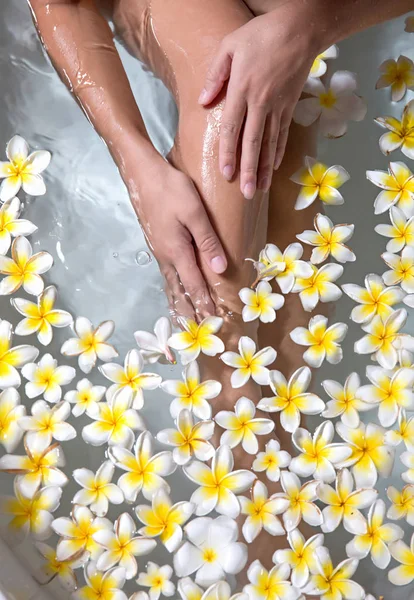 Woman legs in bath tube with flowers spa relaxation body care th