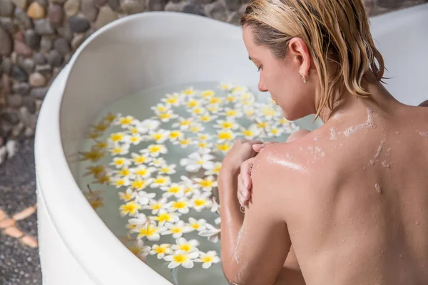 Vrouw ontspannen in Bad met tropische bloemen organische huid zorg l — Stockfoto