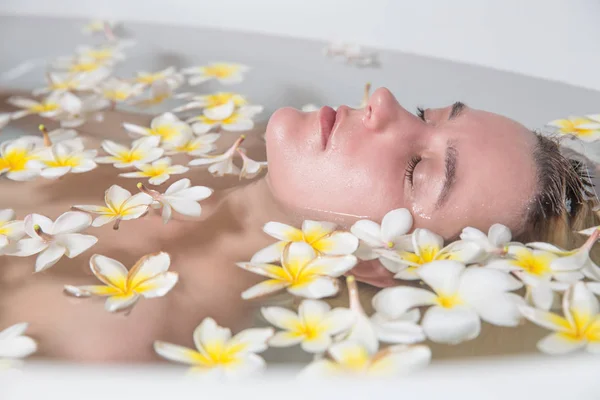 Vrouw ontspannen in Bad met tropische bloemen organische huid zorg l — Stockfoto