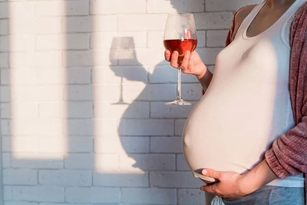 Těhotná žena se sklenicí červeného vína v ruce — Stock fotografie