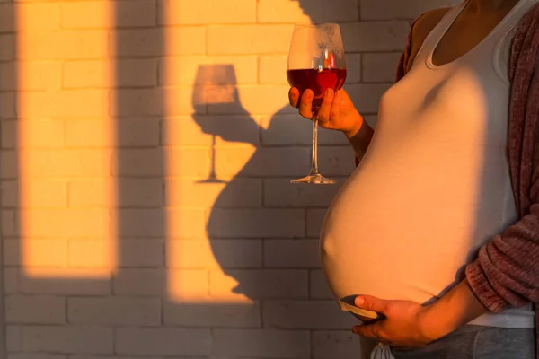 Donna incinta con bicchiere di vino rosso in mano — Foto Stock