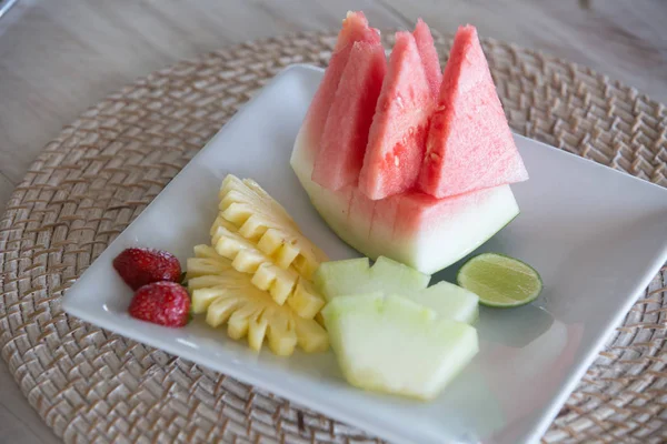 Tropical fruits assortment on a white plate. Fruit plate for breakfast pn plate
