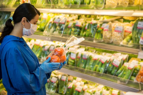 Young woman wears medical mask and protective gloves against coronavirus covid-19 while grocery shopping in supermarket or store- health, safety and pandemic outbreak concept