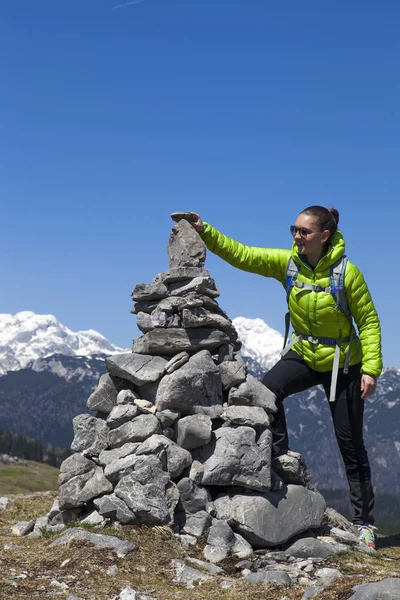 Ragazza felice escursionista mettendo pietre, piccole rocce su pila di pietra, in alto in montagna — Foto Stock