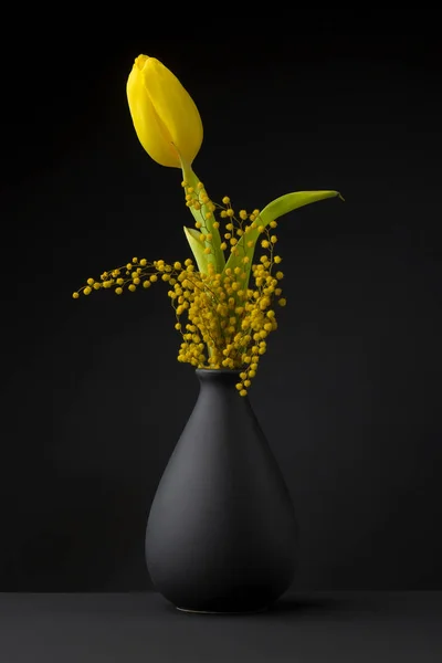 Žlutý Tulipán na černém pozadí stojící v černá váza — Stock fotografie