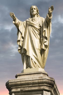 İsa İsa heykeli ile bulutlu gökyüzü ve gündoğumu arka planda.