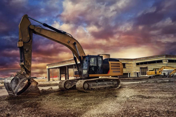 Excavating machinery at the construction site, sunset in background.