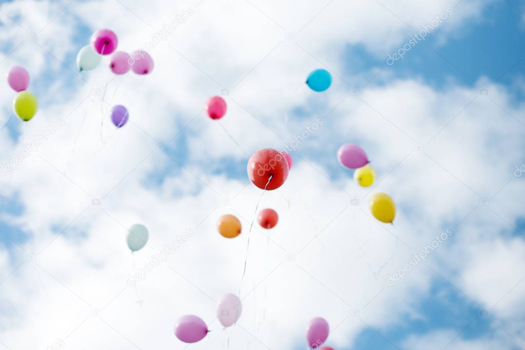 Colorful baloons flying in blue cloudy sky.