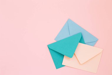 Pembe bir arka plan üzerinde üç renkli zarflar