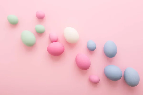 Pembe bir arka plan üzerinde yayılmış Paskalya yumurtaları