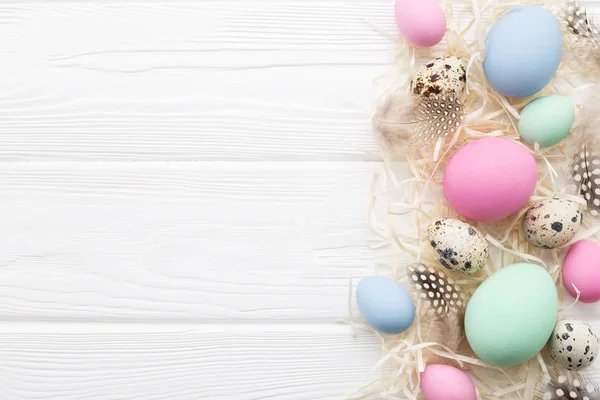 Easter frame with pastel colored eggs on white wooden table — Stock Photo, Image