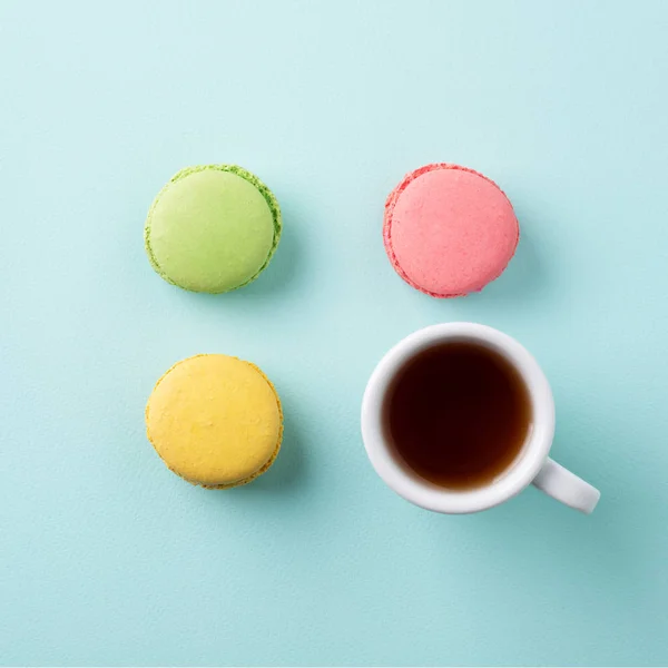 Tasse Tee mit bunten Macarons auf hellblauem Hintergrund Stockbild